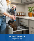 Quiet Bagless Canister Vacuum With Kickass Suction For Whole Home Cleaning emptying large dust cup in kitchen.