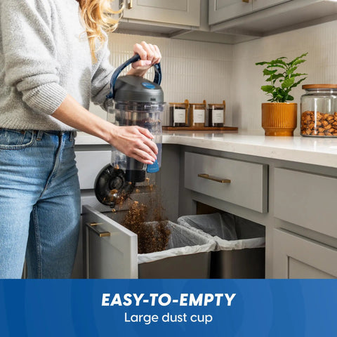Quiet Bagless Canister Vacuum With Kickass Suction For Whole Home Cleaning emptying large dust cup in kitchen.