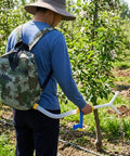 Person using Backpack Manual Spreader Dispenser For Farming 20L Capacity With Bag Easy Carry Durable PVC Construction in orchard