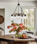 Elwood 25-Inch 5-Light Industrial Rustic Wagon Wheel Chandelier With Clear Glass Globe Shades And Smoked Birch Finish above dining table.
