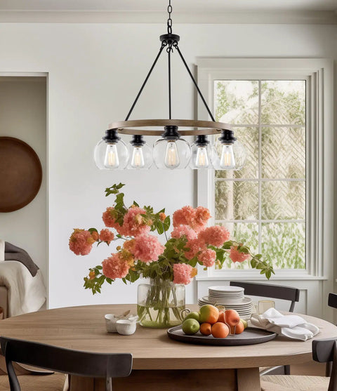 Elwood 25-Inch 5-Light Industrial Rustic Wagon Wheel Chandelier With Clear Glass Globe Shades And Smoked Birch Finish above dining table.
