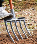Person stepping on Beast 4 Tine Digging Fork For Gardening With High Carbon Steel Spading Tool Heavy Duty Pitch Fork in soil