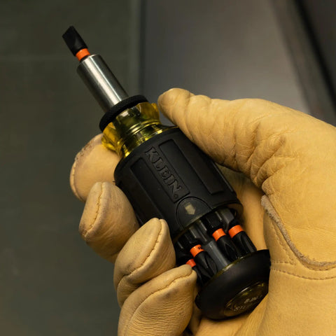 Gloved hand holding 8-In-1 Stubby Screwdriver With Magnetic Handle, Impact Rated And Adjustable Blade, Tiny Yet Tough For Tight Spots.