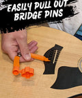 Guitar tool, orange plastic 3-in-1 with string winder and bridge-pin puller on an acoustic guitar