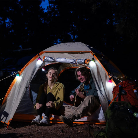 Two people sitting in a tent illuminated by Three Pack Portable LED Camping Lights With Three Modes High Low And Strobe Lightweight ABS Bulbs.
