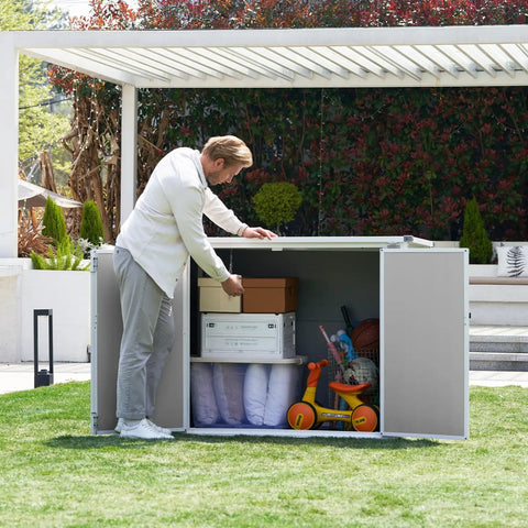 Man organizing items in a spacious outdoor storage shed with floor included, 41 cu ft resin weatherproof storage box, grey and white.