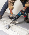 Worker using 5 In. By 11 In. SDS-Plus Bulldog Floor Scraper With Durable Steel Blade for tile removal on floor surface