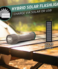 Hybrid Powered LED Flashlight With Solar And AA Battery Options on wooden table with solar panel illustration, outdoors