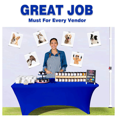 Person at vendor table with animal photos and products, blue tablecloth, market setup.