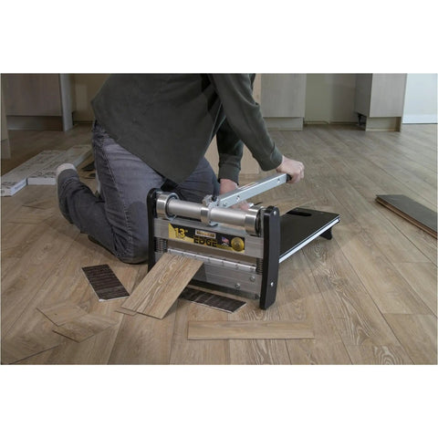 User kneeling with 13 Inch Heavy Duty Lvp Flooring Cutter With Built In Led Light and Reinforced Steel Table, cutting vinyl planks on the floor.