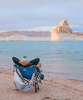 Person relaxing on a beach in a Pod Rocker Outdoor Rocking Chair With SunShade Canopy, Portable Folding Lawn Chair for Patio or Beach