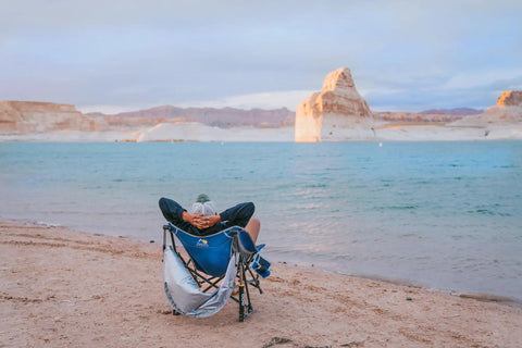 Person relaxing on a beach in a Pod Rocker Outdoor Rocking Chair With SunShade Canopy, Portable Folding Lawn Chair for Patio or Beach