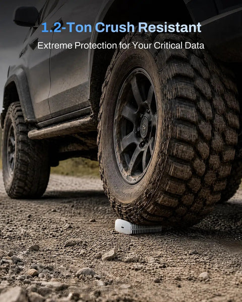 Badass 80Gbps M.2 Nvme Ssd Enclosure under a vehicle tire for extreme data protection and crush resistance on rough terrain.