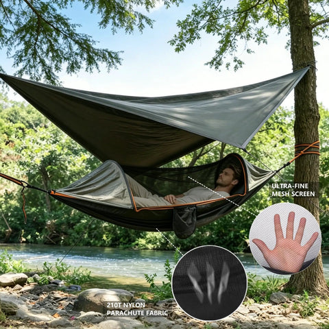 Person relaxing in an All In One Camping Hammock With Mosquito Net And Rain Fly Tarp over a river. Features ultra-fine mesh screen.