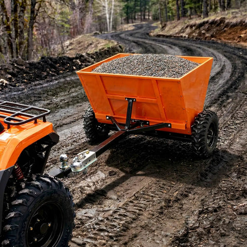 Bright orange 71 gallon tow behind sand and salt spreader for snow and ice control attached to ATV on a muddy rural path