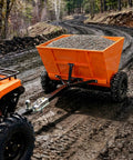 Towable Sand And Gravel Spreader For ATV UTV, 71 Gallon 270 L Capacity, 882 Lb Load, on muddy road with small gravel in hopper