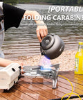 Outdoor camping scene with woman using 2600W Portable Gas Stove With Cassette Design And Multi Stage Adjustable Flame by a lake