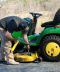 Side view of a yellow LockNLube premium pistol-grip grease gun used on a green riding mower