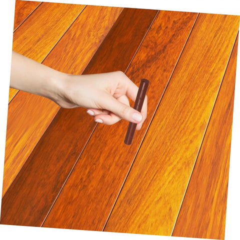 Hand using Dark Brown Wood Repair Kit Wax Filler Sticks For Floors Cabinets And Surfaces Easy To Use No Mess Scratch Repair