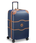 Delsey 26-inch spinner luggage in navy blue with faux leather accents and basketweave texture, featuring durable polycarbonate shell with wheels.