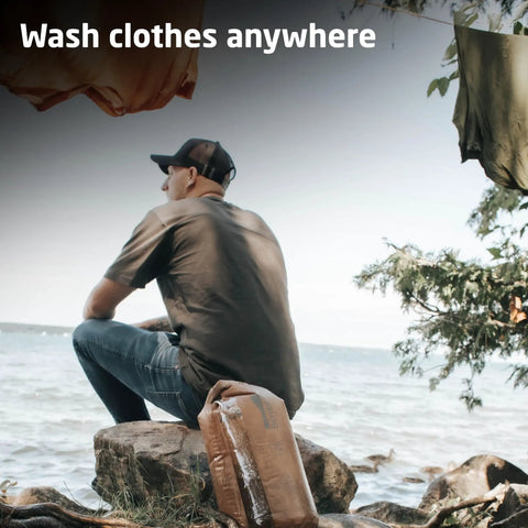 Man at lakeside with Compact Travel Laundry Washbag Featuring Patented Flex Washboard Design for on-the-go cleaning.