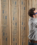 Person installing Top Shelf R-19 Kraft Faced Fiberglass Batt Insulation in framed walls for energy efficiency.