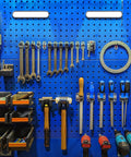 Organized blue pegboard with various tools and hardware neatly arranged on display in a garage or workshop setting.