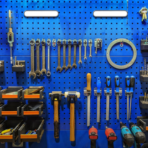 Organized blue pegboard with various tools and hardware neatly arranged on display in a garage or workshop setting.