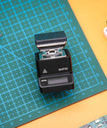 Ultra Compact Mini Hot Plate Soldering Preheater With OLED Display, 60W Power next to soldering tools on cutting mat