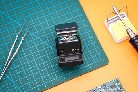 Ultra Compact Mini Hot Plate Soldering Preheater With OLED Display, 60W Power next to soldering tools on cutting mat
