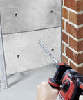 Front view of red cordless hammer drill with 5/32-in SDS-Plus carbide bit; ten masonry drill bits on floor.