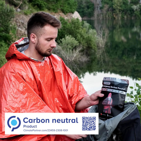 Man wearing orange poncho with package of 4 Pack Emergency Survival Foil Poncho Reversible Thermal Mylar Orange Heat Retention Up To 92 Percent Lightweight Portable Grab And Go Double Sided Rain Gear For Outdoors Camping Hiking And Emergencies