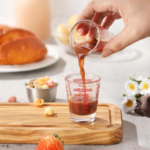 Pouring liquid into Two Pack Shot Glass Measuring Cup Set With Thick Base, Multi Unit Liquid Measuring Cup For Espresso And Drinks, Four Measuring Scales Include 1 OZ, 2 TBS, 6 TSP, 30 ML For Precise Pouring