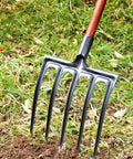 Heavy Duty Garden Digging Fork With High Carbon Steel Tines in use for soil loosening in grass and dirt.