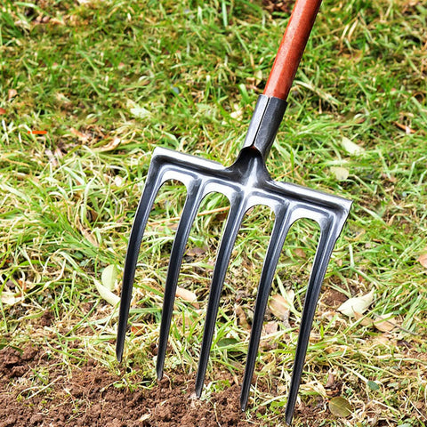 Beefy High Carbon Steel Digging Fork for Garden Use Heavy Duty Spading Tool showing metal tines in soil and grass background.