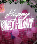 Massive Happy Birthday Neon Sign For Wall Decor With Dimmer Switch in bold white letters among pink balloons and greenery