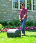 Man using 270 Lb Push And Tow Poly Lawn Roller With Easy Turn Tethered Plug 18 By 24 Inch Flat Black Heavy Duty Drum on grass