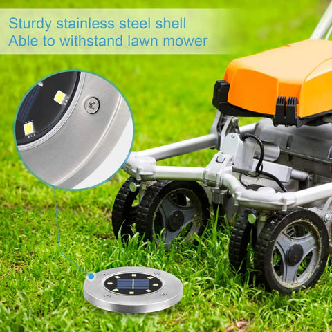 16 Pack Solar Ground Lights Waterproof Outdoor Landscape Pathway Lights with upgraded aluminum build next to a lawn mower.