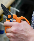 Person holding Floral Scissors Set Of 3 With Carbon Steel Blades For Precise Flower Pruning And Arranging, warm orange handle