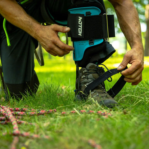 Man adjusting Steel Tree Climber Gaffs With Ergonomic Shank And 20 Plus Cuff Adjustment Points on grass.