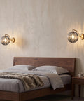 Mid‑Century Modern Globe Glass Wall Sconce with Wine Red Hand‑Blown Glass illuminating a stylish bedroom wall.