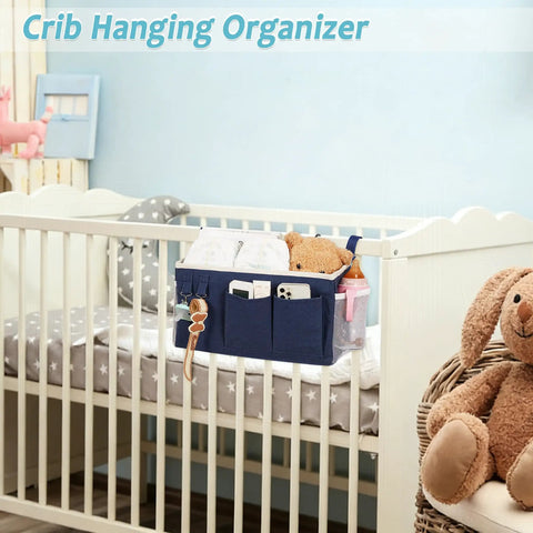 Bedside Caddy Hanging Organizer For Beds And Rails attached to crib with pockets holding diapers, toys, and phone, navy blue.