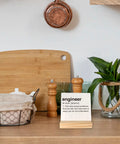 Engineer Definition Wood Plaque Sign Gift For Engineers Office Decor Desk Display on kitchen counter with plants and jars.
