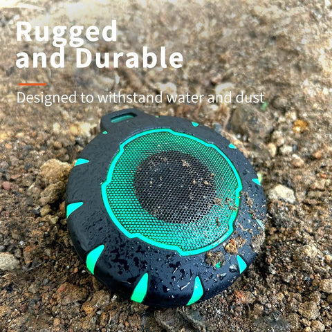 Waterproof Shower Bluetooth Speaker With IPX7 Rating, Ultra Portable Carabiner Clip on muddy ground emphasizing durability.