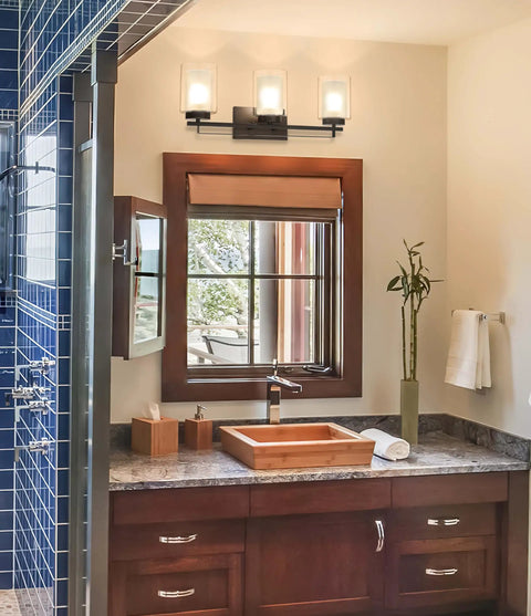 Dope 3 Light Bathroom Vanity Light In Dark Bronze With Dual Glass Shades over mirror in modern bathroom setting.