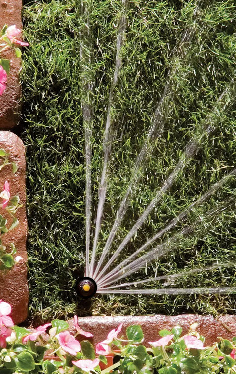 Pro Rotary Sprinkler With PRS Pressure Regulation, High-Efficiency Rotor, Hand Adjustable 45 To 270 Degree Pattern, 13 To 18 Foot Spray, 4 Inch Pop-Up, Water-Saving Design Delivers Constant 30 Psi spraying water on grass and flowers.