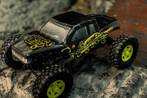 Juice Up Four By Four One Eighteen Scale RC Crawler Pro Brushless Power System Ready For Off Road Action With Waterproof HBW Electronics Two Four Gigahertz Four Channel Radio For Adults Yellow on rocky terrain.