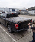 Man securing Heavy Duty Waterproof Tarp With Bionic Tree Camo Pattern on truck bed, showcasing versatility and durability.