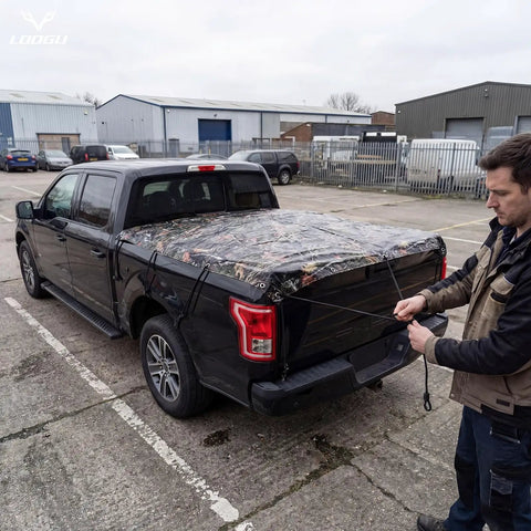 Man securing Heavy Duty Waterproof Tarp With Bionic Tree Camo Pattern on truck bed, showcasing versatility and durability.