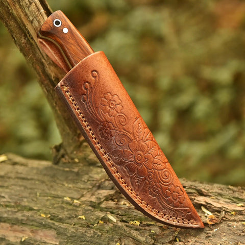 Full Tang Hunting Knife With 10 Inch Overall Length, 5 Inch High Carbon Steel Blade, Rosewood Handle, And Sheath displayed on wood